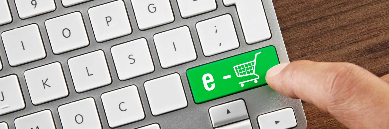 Computer keyboard with white keys and one key in green with a shopping cart image